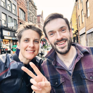 A photograph of Sarah E. Truman and David Ben Shannon smiling on the street in Manchester's Northern Quarter. 